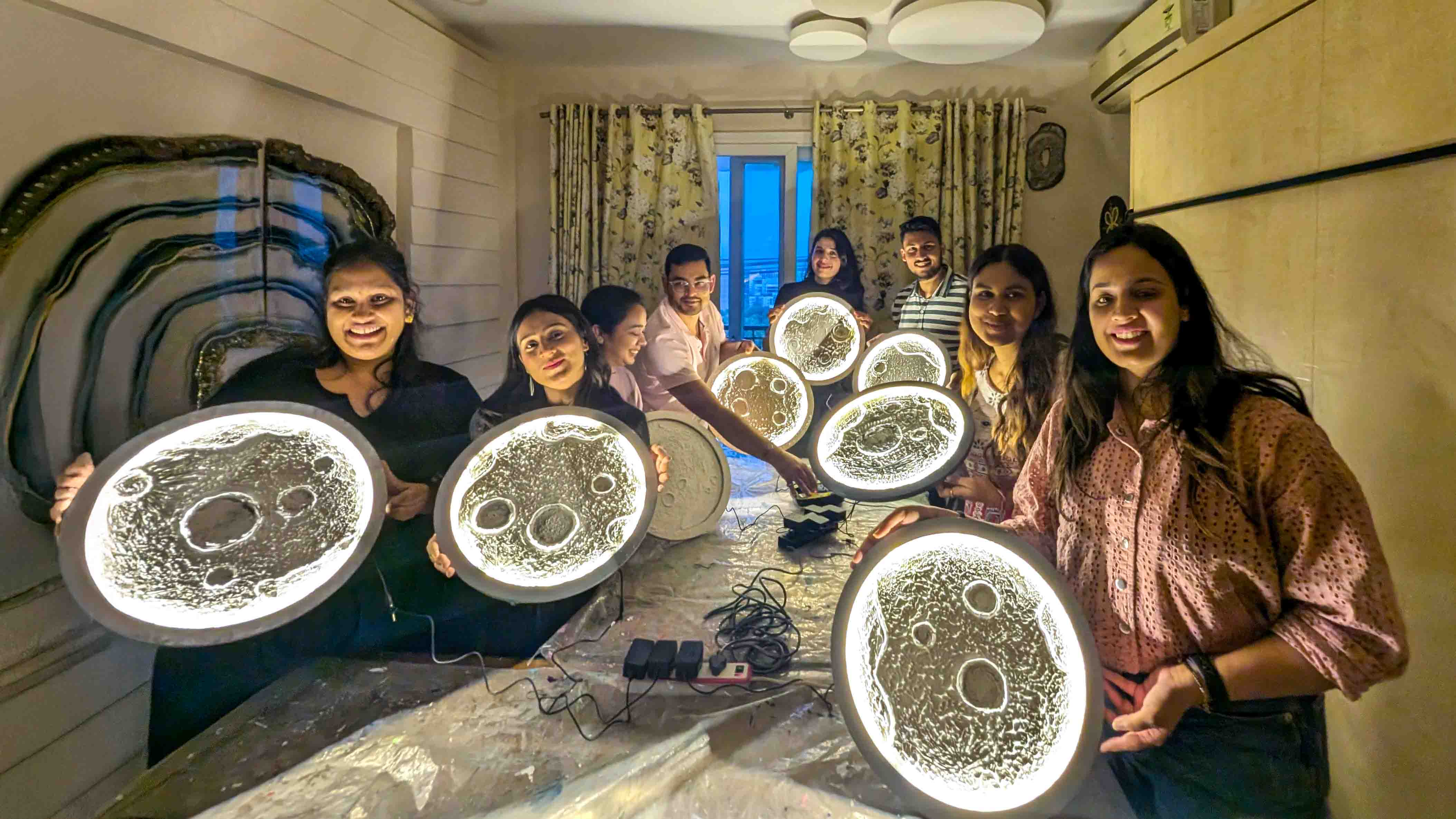 Woman admiring and holding her glowing finished moon lamp with pride and joy.